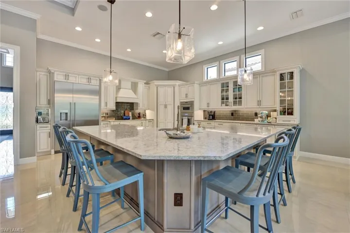 Kitchen with light tile floors, backsplash, appliances with stainless steel finishes, and a large island