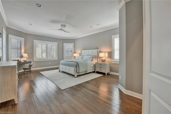 Bedroom with dark wood-type flooring, ornamental molding, and ceiling fan