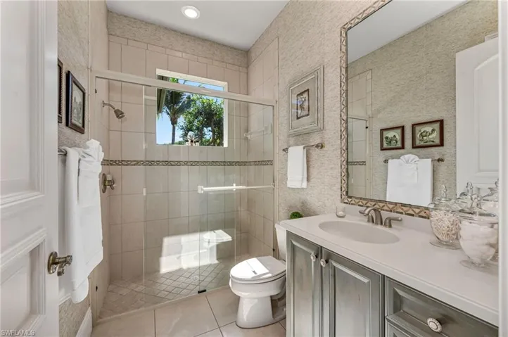 Guest bath has large, walk-in shower, beautiful wallpaper and detailed, custom marble inlays around mirror and on shower wall.