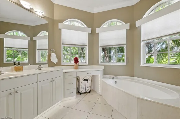 Master Bathroom with double vanity, crown molding, a bath, and light tile patterned floors