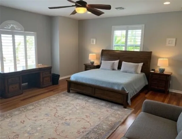 Bedroom with ceiling fan, hardwood / wood-style flooring, and multiple windows