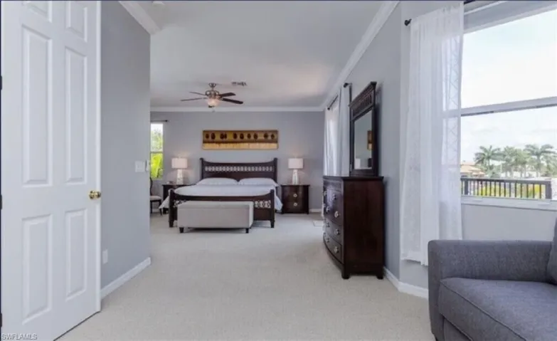 Carpeted bedroom featuring ceiling fan and ornamental molding
