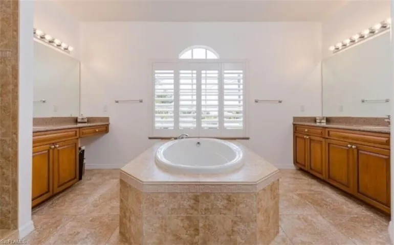 Bathroom featuring tile patterned floors, a relaxing tiled tub, and vanity