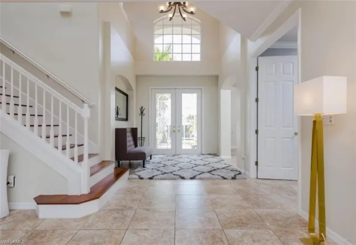 Tiled entrance foyer featuring a high ceiling, a chandelier, and french doors