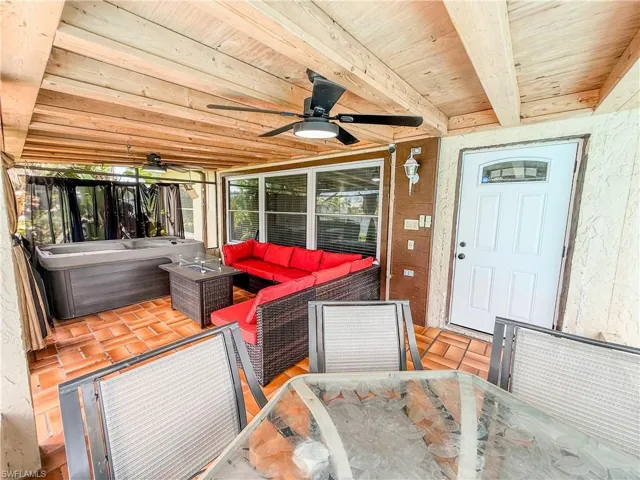 Sunroom with ceiling fan, an outdoor hangout area, outdoor dining area, and beamed ceiling