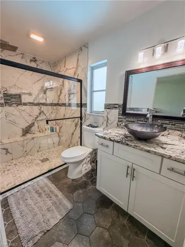 Bathroom featuring vanity and a marble finish shower