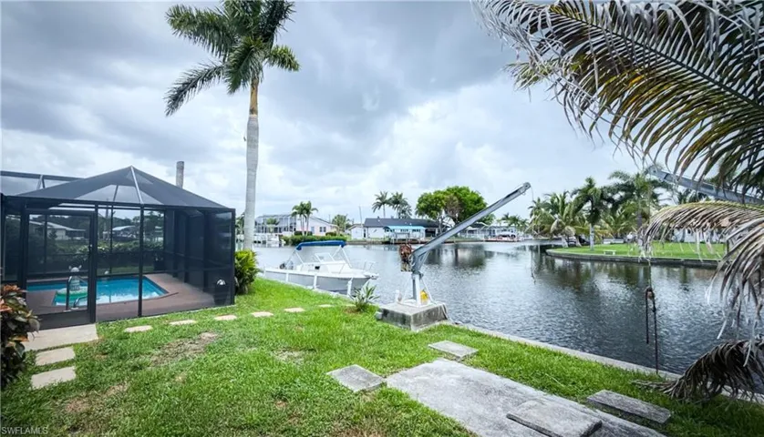 View of green lawn featuring a water view, an outdoor pool, and glass enclosure