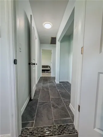 Hallway featuring baseboards and dark marble finish flooring