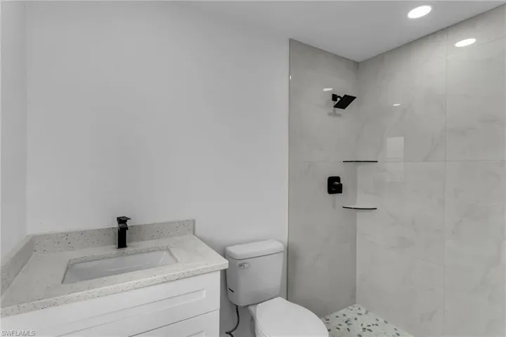 Bathroom with toilet, vanity, and tiled shower