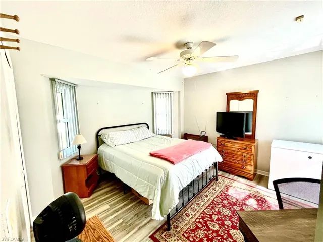 Bedroom featuring ceiling fan, light hardwood / wood-style floors, and a textured ceiling
