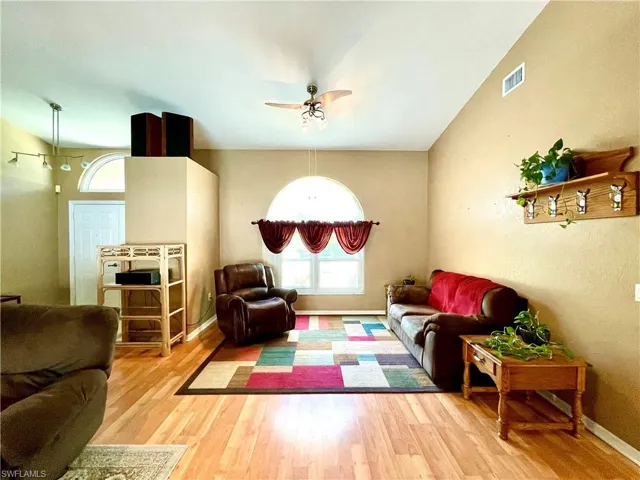 Living room featuring ceiling fan, wood-type flooring, and vaulted ceiling