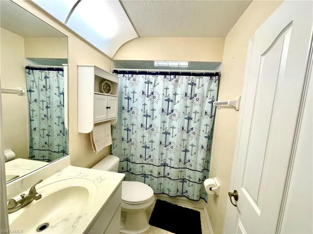 Bathroom featuring a shower with curtain, vanity, a textured ceiling, and toilet