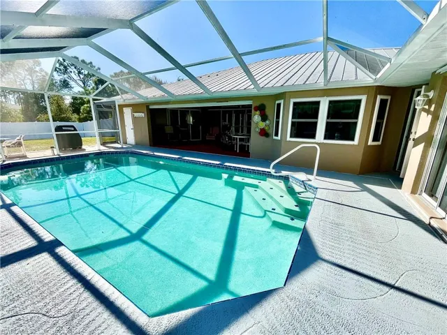 View of swimming pool with a patio and glass enclosure