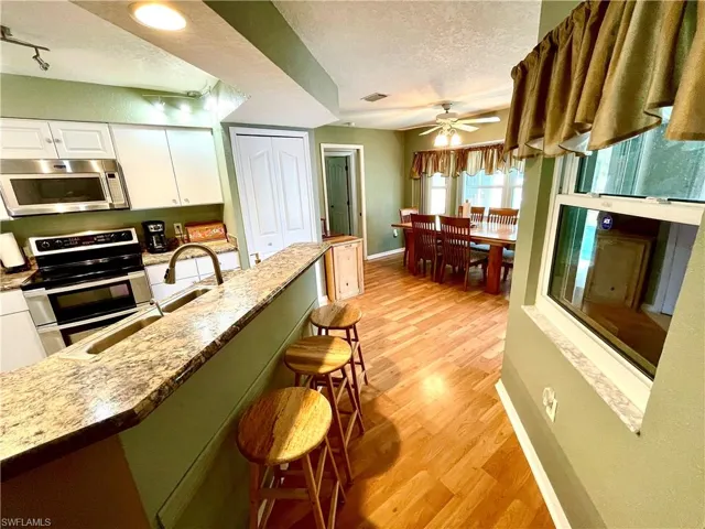 Kitchen with a breakfast bar, white cabinets, rail lighting, a textured ceiling, and stainless steel appliances