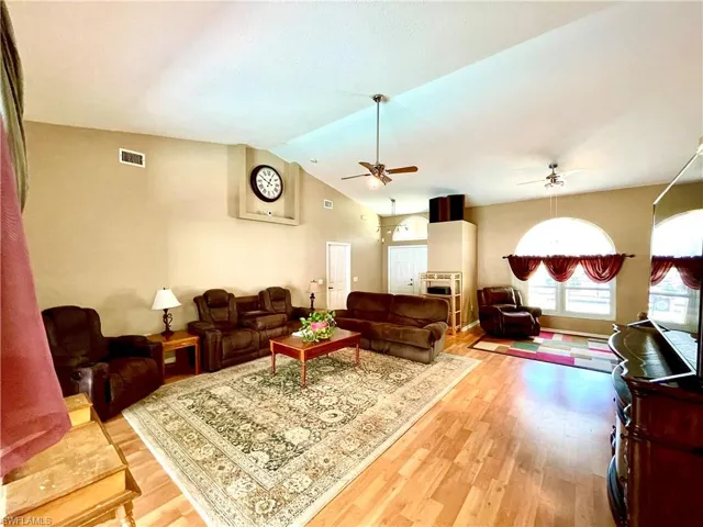 Living room featuring hardwood / wood-style flooring, ceiling fan, and vaulted ceiling