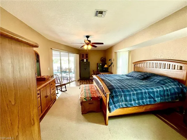 Carpeted bedroom with access to outside, ceiling fan, and a textured ceiling