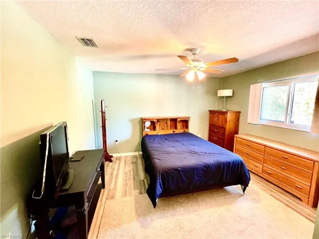 Bedroom featuring ceiling fan, light wood-type flooring, and a textured ceiling