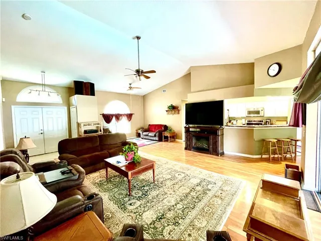 Living room featuring light wood-type flooring, ceiling fan, and lofted ceiling