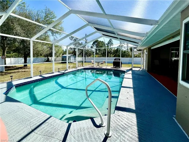 View of pool featuring a lawn, a storage unit, and a lanai