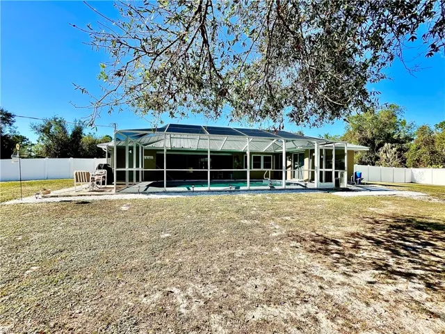 Rear view of house with a lanai, a fenced in pool, and a yard