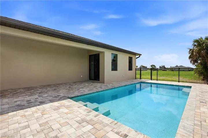 Backyard featuring an in-ground swimming pool with integrated steps, surrounded by extensive paver decking