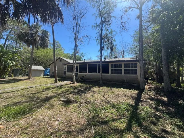 Rear view of house featuring a storage shed, a lawn, and a sunroom