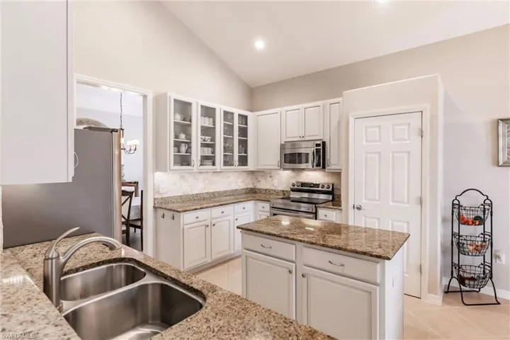 Kitchen featuring granite counters, stainless steel appliances, white cabinets, and kitchen island