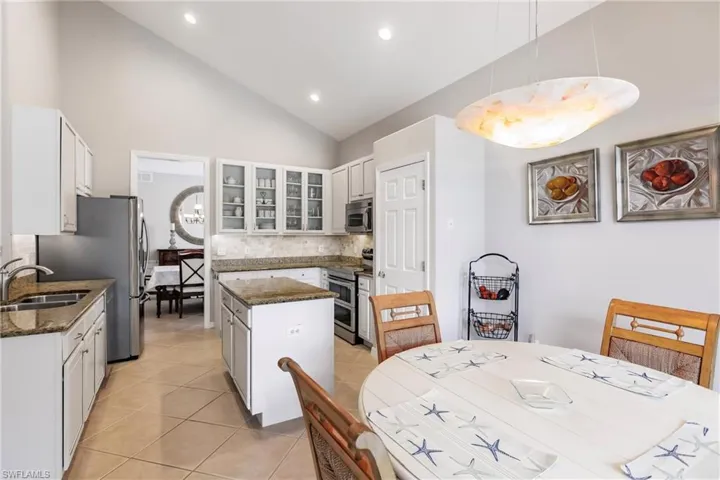 Kitchen featuring granite counters, stainless steel appliances, white cabinets, and kitchen island