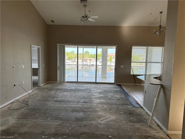 Empty room featuring ceiling fan with notable chandelier
