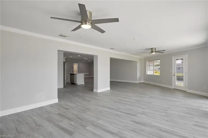 Unfurnished living room with light wood-type flooring, baseboards, and ornamental molding