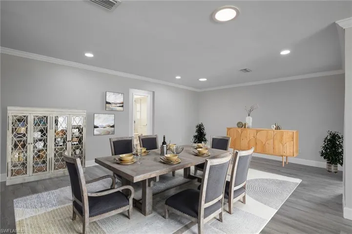 Staged Dining area with ornamental molding, wood finished floors, visible vents, and baseboards
