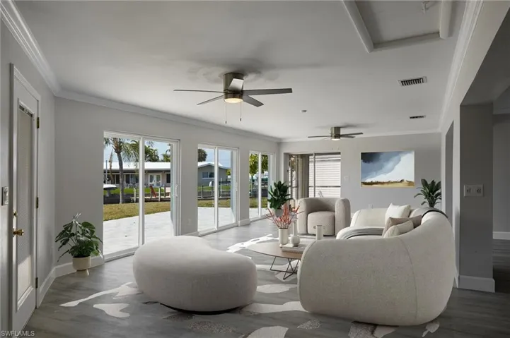 Staged Living area featuring ornamental molding, wood finished floors, visible vents, and baseboards
