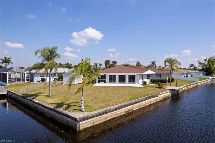 Rear view of house featuring a yard, a water view, and fence