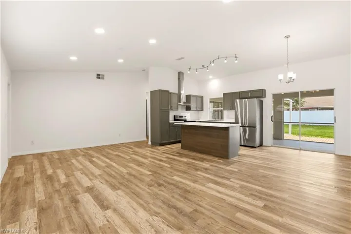 Kitchen with open floor plan, a kitchen island, stainless steel appliances, suspended lighting, and light countertops