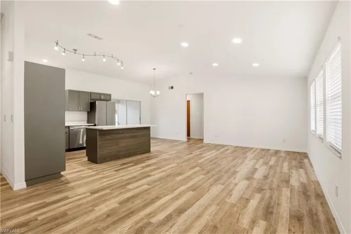 Kitchen with open floor plan, light countertops, a center island, stainless steel appliances, and light wood-style flooring