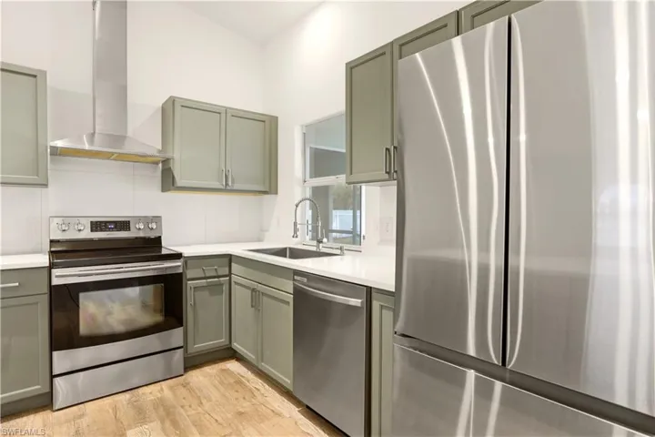 Kitchen with stainless steel appliances, light wood finished floors, and gray cabinetry
