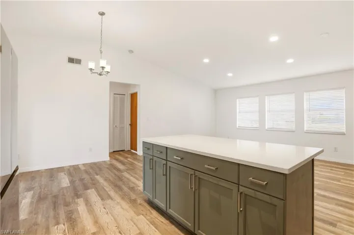 Kitchen featuring lofted ceiling, a center island, light wood-type flooring, and a chandelier