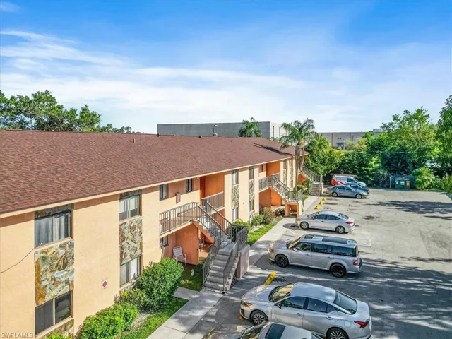 View of property with stairway and uncovered parking