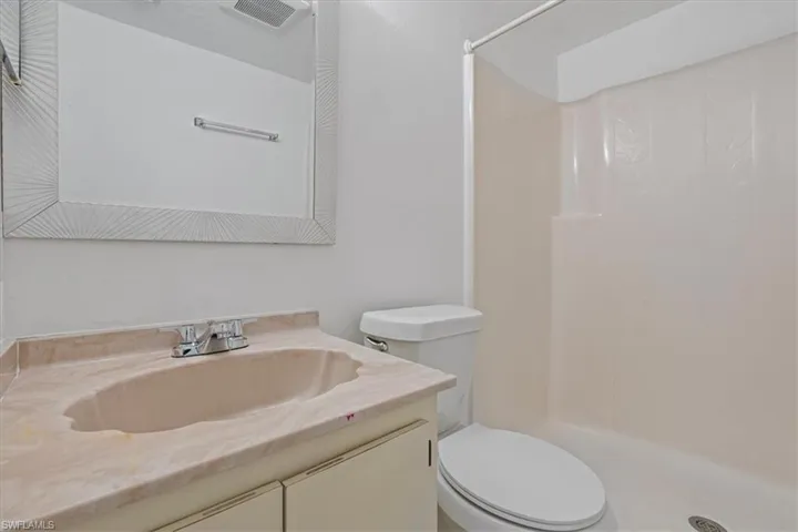Bathroom with vanity, toilet, visible vents, and a stall shower