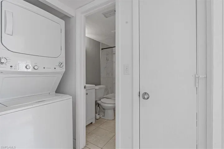 Laundry area featuring light tile patterned floors, laundry area, and stacked washer and dryer