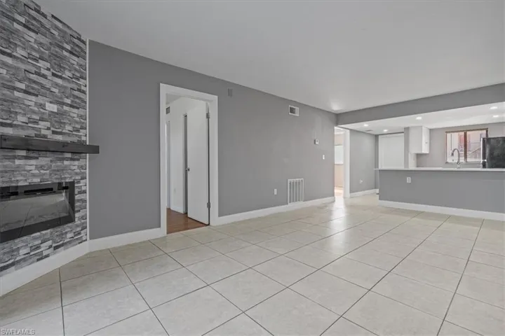 Unfurnished living room featuring light tile patterned floors, visible vents, baseboards, and a fireplace