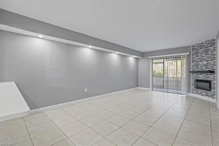 Unfurnished living room with tile patterned flooring, baseboards, and a large fireplace