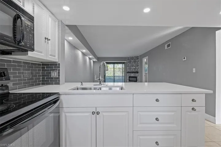 Kitchen featuring visible vents, backsplash, light countertops, black appliances, and a sink