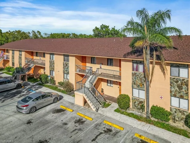 View of property with stairway and uncovered parking