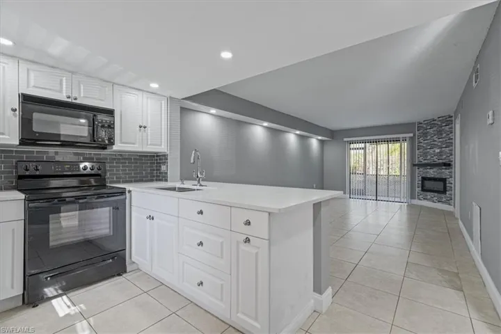 Kitchen featuring black appliances, a peninsula, light countertops, and a sink