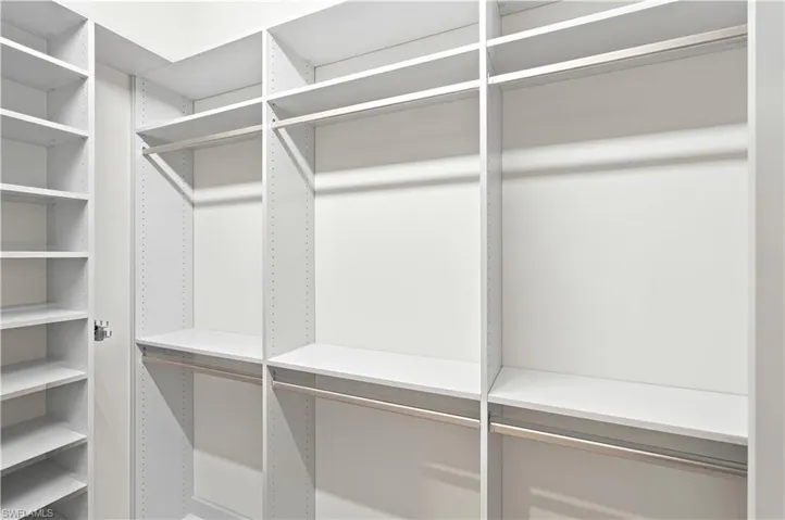 Custom closet system featuring white shelving and chrome hanging rods