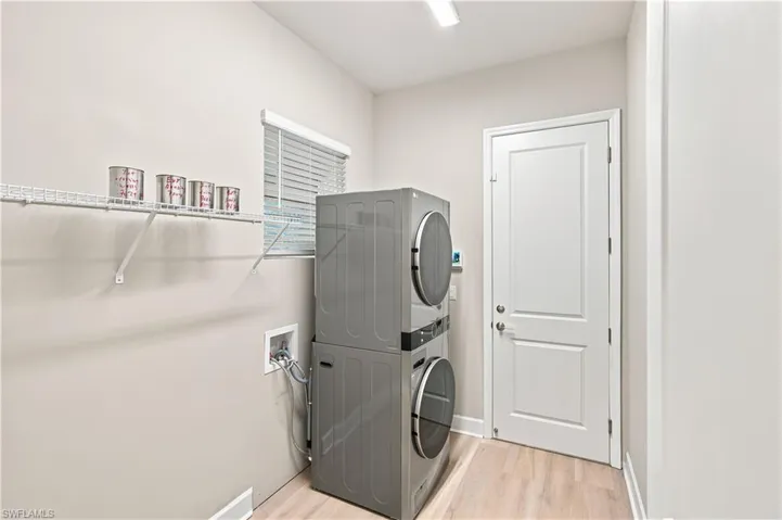 Dedicated laundry space featuring light wood-finish flooring, a window with blinds, and white wire shelving