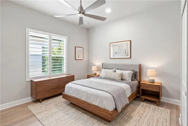 Guest Room 2 Room Digitally Staged  Bedroom featuring wood-finish flooring, a ceiling fan with integrated lighting, recessed lighting, and a window with white plantation shutters