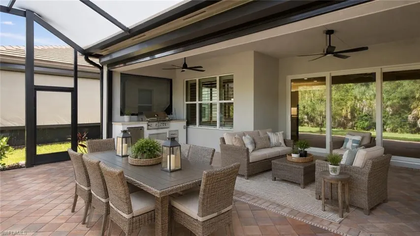 Room Digitally Staged  Extended Screened lanai featuring a built-in outdoor kitchen, recessed lighting, outdoor kitchen, ceiling fans, and a paver patio