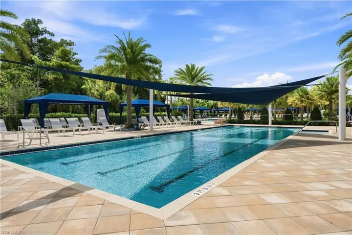 Rectangular swimming pool with lane markers, paver pool deck, and shade sails